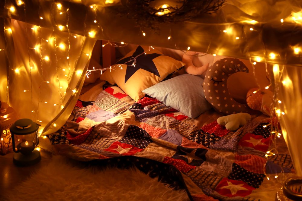blanket fort with string lights and pillows